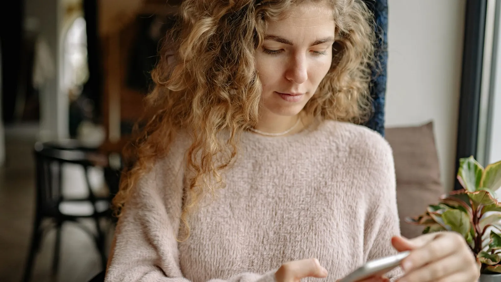 A woman in a sweater reading a message on her phone